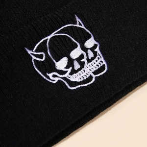 Détail de la broderie de crâne blanc sur un bonnet en maille côtelée noire