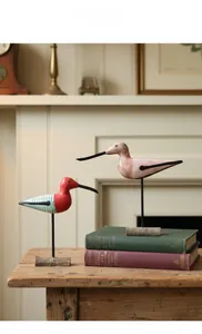 Macro detail of two Nordic hand-painted wooden bird ornaments on metallic stands