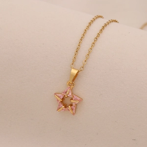 Detailed macro view of the gold star pendant inlaid with pink zircon on a chain