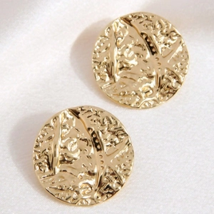 Elegant pair of round gold stainless steel earrings with hammer texture on white silk