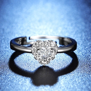 Macro shot of silver heart-shaped moissanite ring with halo setting on dark blue background