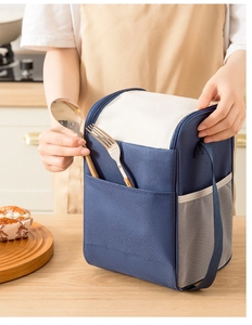 Detail showing the front storage pocket for utensils on a navy blue insulated lunch bag
