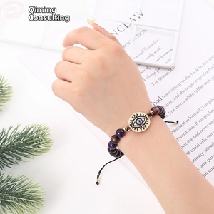 Detailed shot of purple stone beaded bracelet with gold evil eye charm on wrist