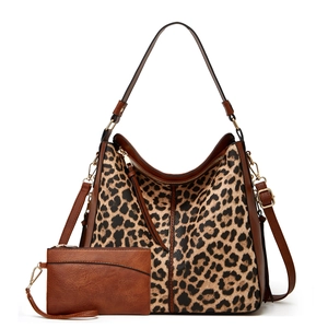 Detail view of leopard print tote bag with brown leather accents and small matching clutch