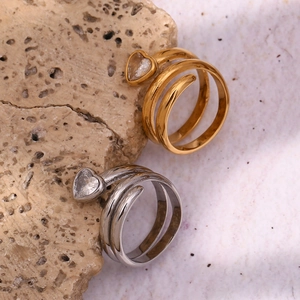 Detail of 18K gold and silver heart-shaped zircon rings on natural stone background