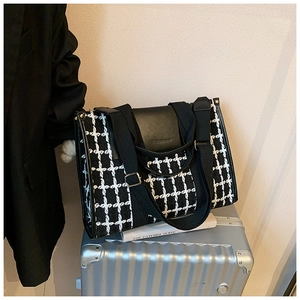 Close-up of houndstooth tote bag on luggage featuring black PU leather flap and straps