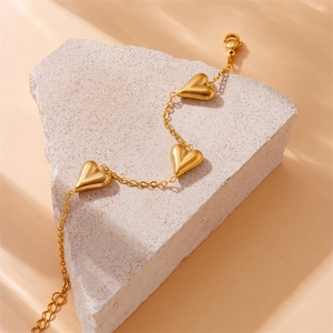 Gold plated heart tassel bracelet on a stone pedestal with elegant light and shadow