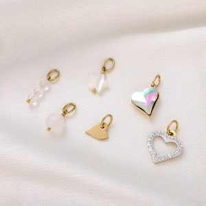 Detailed close-up of golden heart and star pendants with beads on white silk fabric