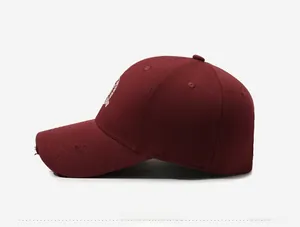 Side view of vintage burgundy baseball cap with white shield embroidery and distressed brim
