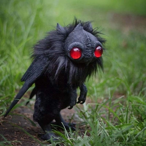 Αρθρωτή μαύρη φιγούρα μωρού Mothman με κόκκινα μάτια σε φυσικό περιβάλλον με γρασίδι