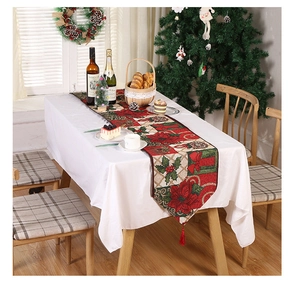 Christmas table runner with festive poinsettia patterns and red tassels in cozy setting