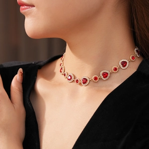 Primo piano di una collana vintage a cuore con gemma rossa e diamanti indossata da modella