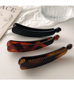 Close-up of matte black and amber tortoiseshell banana hair clips on a clean background