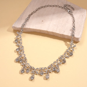 Detail of silver vintage bow necklace with crystal water drop pendants on stone base