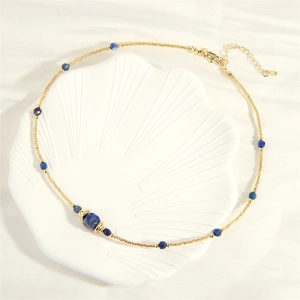Detail of beaded necklace with blue lapis stones on a white shell ceramic tray