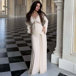 Detail of the elegant V-neck lace trim and waist tie design on a cream long-sleeved dress