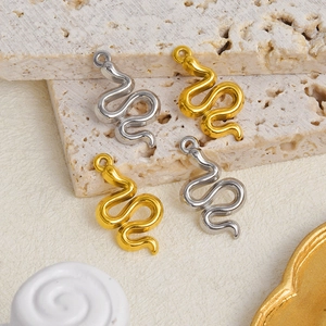 Detailed close-up of snake pendants in gold and silver finishes on natural stone surface