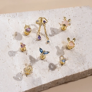 Collection of golden heart and butterfly zircon stud earrings on natural stone