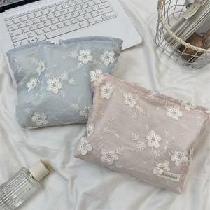 Detailed view of floral embroidery on pastel cotton linen cosmetic storage bags
