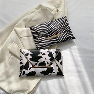Chic zebra and cow print envelope clutch bags with gold metal trim on white fabric