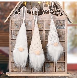 Three knitted Christmas gnome ornaments with hats and plush beards on wooden calendar background
