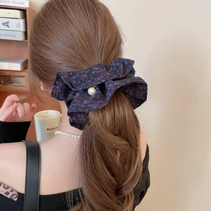 Detail of blue leopard print scrunchie with pearl charm worn on hair in lifestyle setting