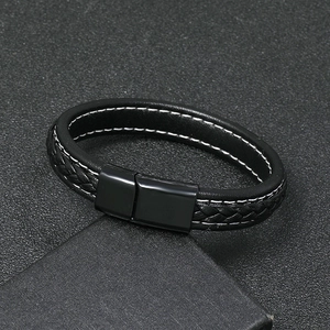 Close-up of black braided leather bracelet with magnetic metal clasp on textured surface