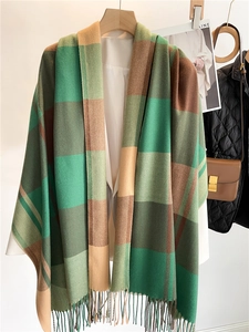 Dettaglio della sciarpa a quadri tipo cashmere con frange su una gruccia di legno