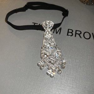 Macro shot of sparkling rhinestone necktie pendant with tassels and silver geometric details