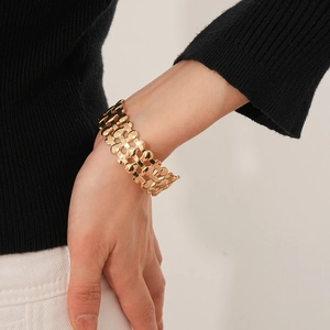 Detailed view of wide gold woven cuff bracelet with polished triple-layer chain texture