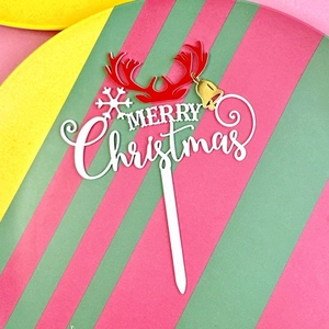 Detail of white Merry Christmas acrylic cake topper with red antlers and gold bells