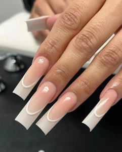 Dettaglio di unghie finte French rosa nude con bordo bianco e forma a bara lunga
