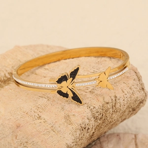Elegant gold butterfly bracelet with black wings and crystal accents on natural stone