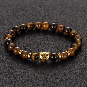 Macro detail of natural tiger eye beaded bracelet with vintage gold owl charm