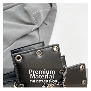 Macro detail of gothic crossbody bag with metallic rivets and vintage cross pendant