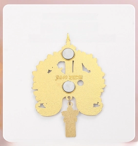 Détail de l'aimant de frigo en métal doré avec deux aimants circulaires et pendentif fleur