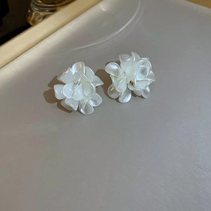 Detailed view of 3D layered white floral stud earrings with pearl finish on a tray