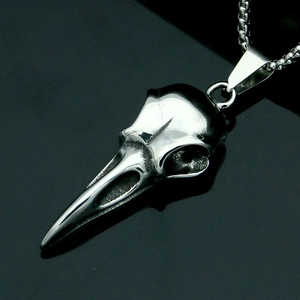 Macro detail of silver eagle skull pendant in polished stainless steel on a dark surface
