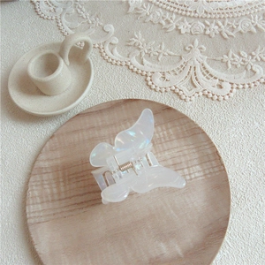 Iridescent butterfly hair claw clip in acetate on a minimalist wooden tray display