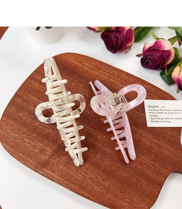 Detail of marble pattern acetate hair claws in beige and pink with metal spring on wood