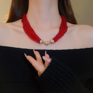 Detail of multi-layered red bead necklace with a crystal-encrusted gold magnetic clasp
