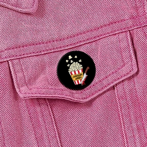 Enamel lapel pin with popcorn and bloody knife on pink denim jacket pocket