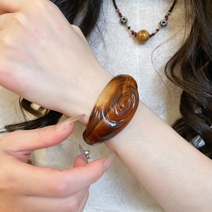 Macro detail of amber resin spiral bangle showing glossy finish and unique grooved texture