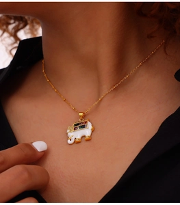 Close-up of golden elephant pendant with white enamel and colorful gemstones on model