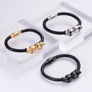 Close-up of punk skull braided leather bracelets in gold, silver and black with magnetic clasp