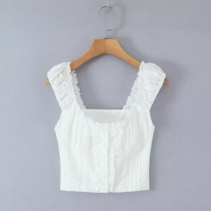 White sleeveless cotton crop top with eyelet embroidery and ruffle straps on a wooden hanger