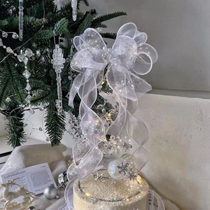 White organza bow Christmas cake topper with fairy lights and tree decor for holiday parties