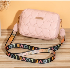 Close-up of pink heart-quilted small square bag with colorful LOVE print strap