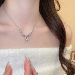 Close-up of sparkling V-shaped zircon flower pendant necklace worn on elegant model