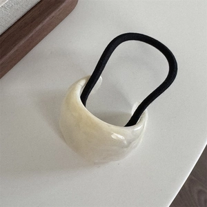 Close-up of a glossy creamy white acrylic bead on a black elastic hair tie hair accessory
